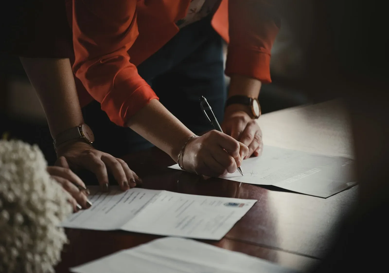 person in orange long sleeve shirt writing on white paper